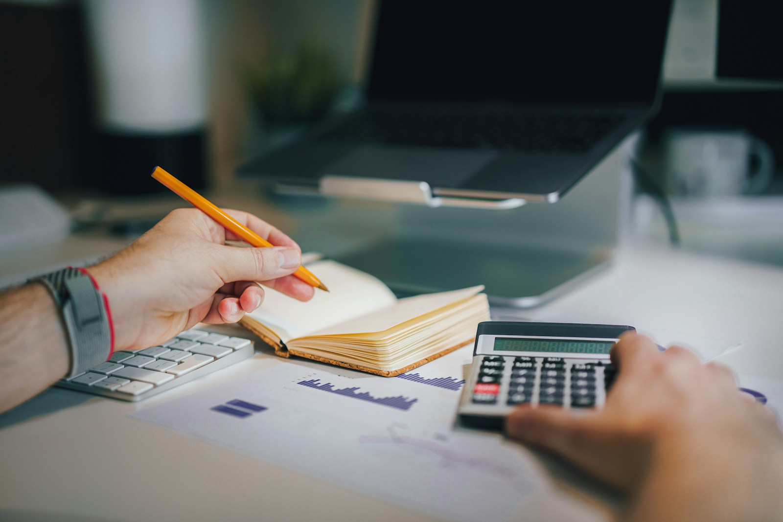 Photo by Jakub Żerdzicki a person sitting at a desk with a calculator and a notebook